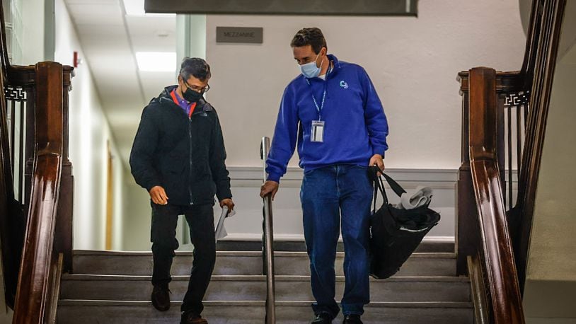 Two City of Dayton employees walk down steps from the mezzanine level at city hall Friday January 6, 2023. The city of Dayton is requiring all employees to wear masks at work due to elevated local COVID levels. JIM NOELKER/STAFF