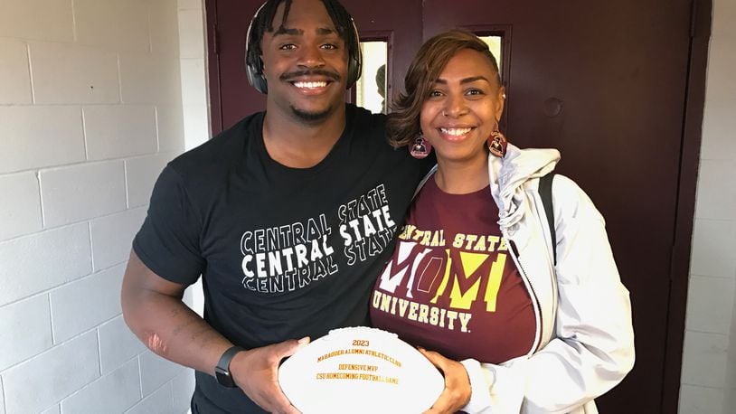 Central State defensive lineman and Springfield native Mike White presents the defensive game ball he was awarded Saturday to his mother Rebekah Howard, a Springfield South grad who now lives in Columbus. White had 11 tackles, including six for loss, in CSU's 21-10 win over Savannah State. Tom Archdeacon/CONTRIBUTED