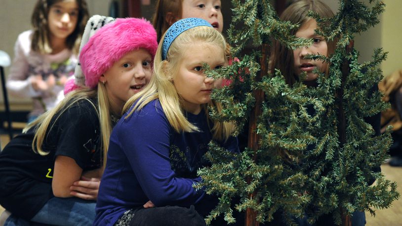 Cautious Munchkins hide among the trees in the Muse Machine's production of "The Wizard of Oz."