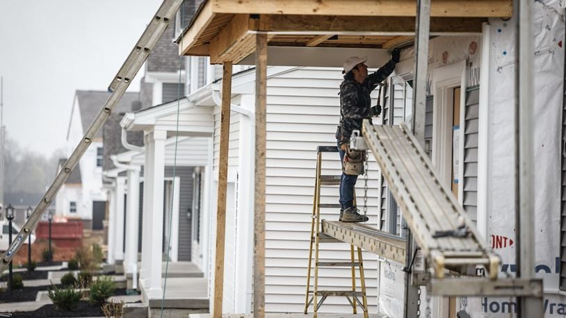 Nestor Uzhca hangs siding on a newly constructed house on Chamberlin Drive in Miamisburg Wednesday, April 10, 2024. Total new permits pulled for 2023 numbered 1,697, down 14.8% from 2022, according to Home Builders Association of Dayton. JIM NOELKER/STAFF