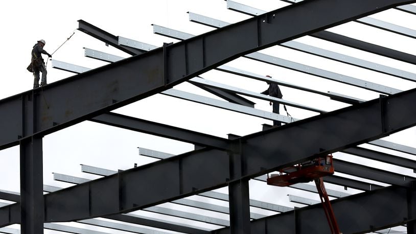 Construction workers guide a roof beam into place as work continues on the second phase of the Topre plant. Bill Lackey/Staff