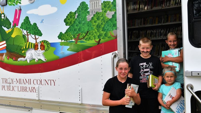 Members of the Twiss family in Troy’s Westbrook neighborhood visit the Troy-Miami County Public Library bookmobile that has been praised for its exterior graphics. CONTRIBUTED