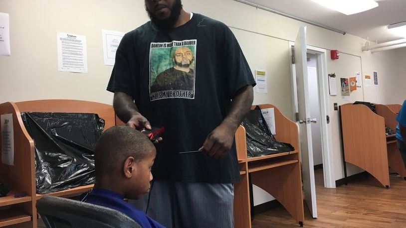 David Carter, a barber at Dacoldest Cuts barber shop, volunteers to give kids free hair cuts at a “after school rally” at Desoto Bass. Event organizer Will Smith said supports like this are what Dayton’s children need to improve school test scores.