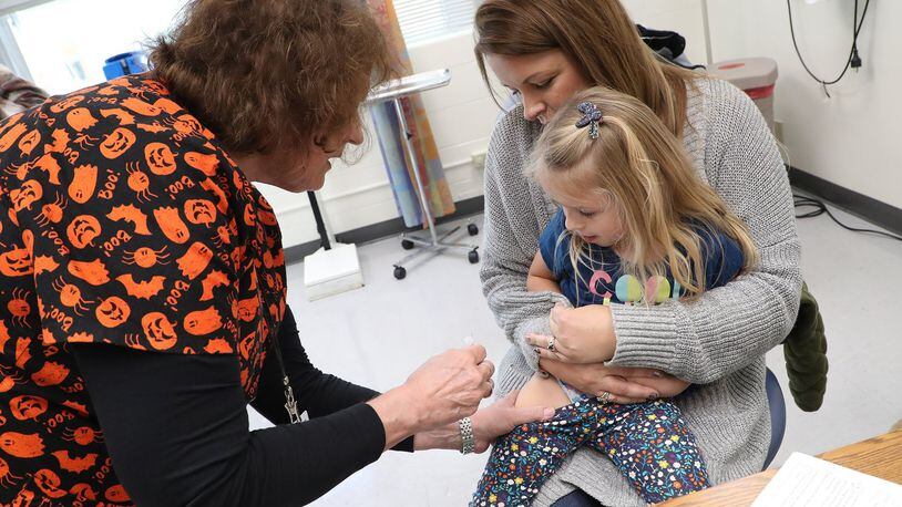Jennie Rohrer, a registered nurse at the Clark County Combined Health District, gives Willow Brooks, 3, a flu shot as her mother, Tammy, holds her Wednesday. BILL LACKEY/STAFF