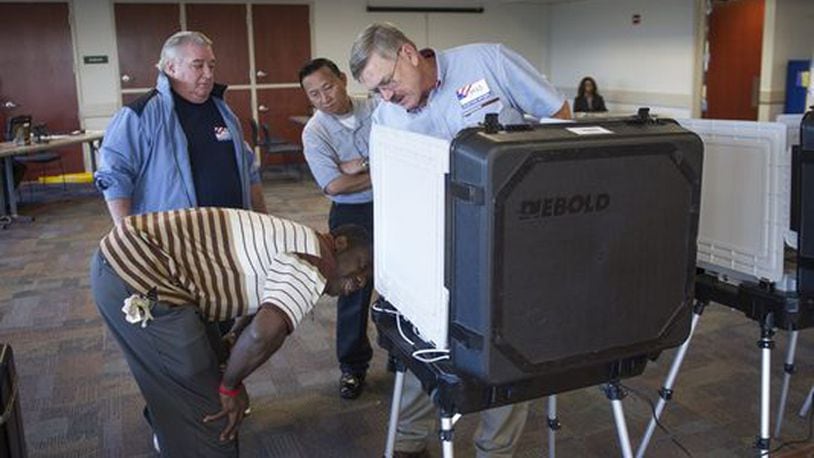 Poll workers work on what they believe to be a malfunctioning electronic voting machine in Duluth, Ga., on Oct. 24, 2014.