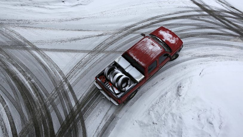 In this Thursday, Dec. 29, 2016, file photo, the driver of a pickup appears to have swapped out his general use tires, in the truck’s bed, in favor of snow tires just in time to deal with the snow-covered streets of Auburn, Maine. Experts say if the rubber on your tires is worn, you could slide, crash or get stuck, even in a light snowfall. Depending on where you live and how badly you need to get someplace in bad weather, you might want winter tires. All-season tires might be an option, but they won’t start and stop as well in ice and snow. (AP Photo/Robert F. Bukaty, File)