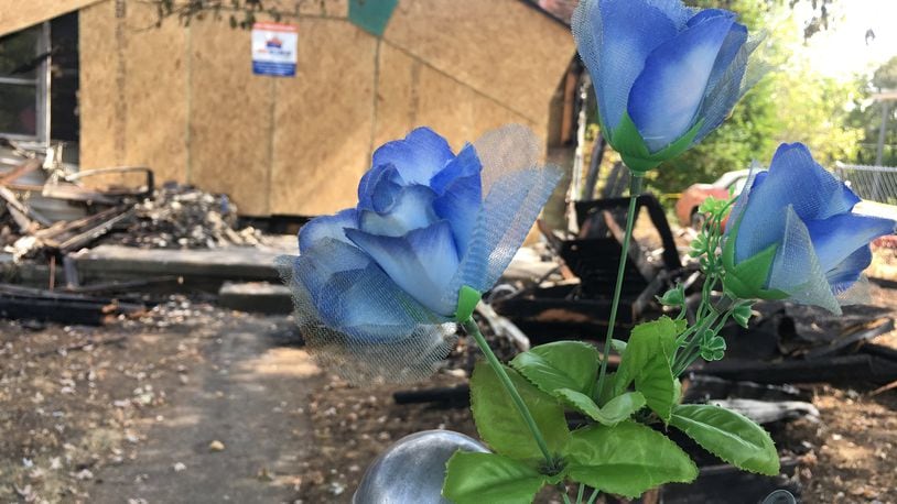 Three artificial blue flowers were attached to a chain-link fence outside a home on Parrish Avenue that caught fire Saturday afternoon. MICHAEL D. PITMAN/STAFF
