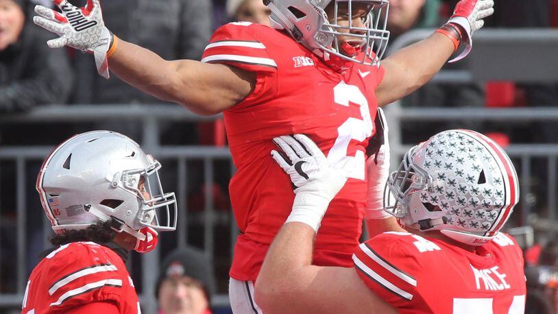 Ohio State’s Billy Price lifts J.K. Dobbins after a touchdown against Michigan State on Saturday at Ohio Stadium in Columbus. On the Buckeyes’ first score, a 47-yard burst up the middle by running back Mike Weber, Price had two key blocks. DAVID JABLONSKI / STAFF