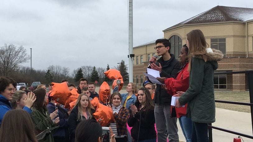 Riley Weisman, (left), a junior at Springboro High School, speaks at the walkout at Springboro High School, as schoolmates Suhavi Salmon and Ella Bowman (right) join him in front of about 500 students in the school’s parking lot Wednesday. LAWRENCE BUDD / STAFF