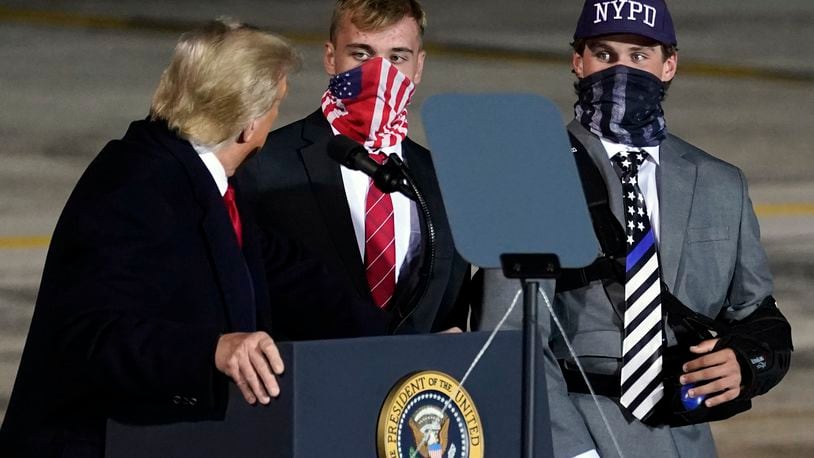 President Donald Trump brings two football players from Little Miami High School who were suspended for a short time for carrying flags that showed support for law enforcement at the start of a game on Sept. 11, onto stage as he speaks during a campaign rally at Eugene F. Kranz Toledo Express Airport, Monday, Sept. 21, 2020, in Swanton, Ohio. (AP Photo/Alex Brandon)