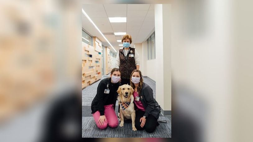 Karen Muller, middle, is with Kara Lucas, left, and Meghan King and one of the service dogs that makes visits with children at Dayton Children's Hospital.