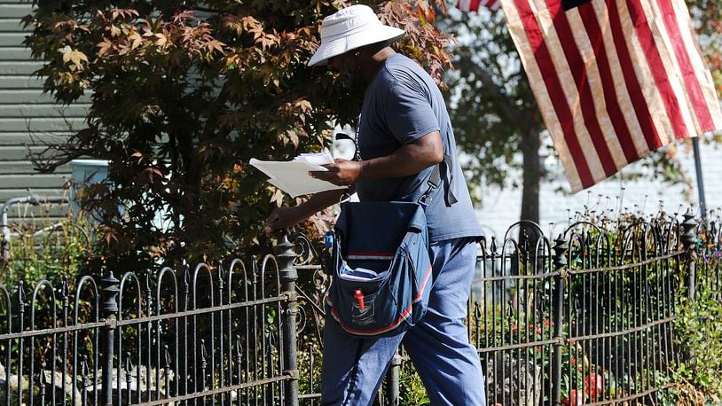 A postal worker delivers his route on Oak Street Wednesday, Oct. 18, 2023 in Dayton. MARSHALL GORBY\STAFF