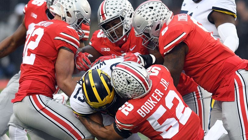 Several Ohio State defenders take down Michigan’s Tru Wilson during the first half of Saturday’s game at Ohio Stadium. Nick Falzerano/CONTRIBUTED