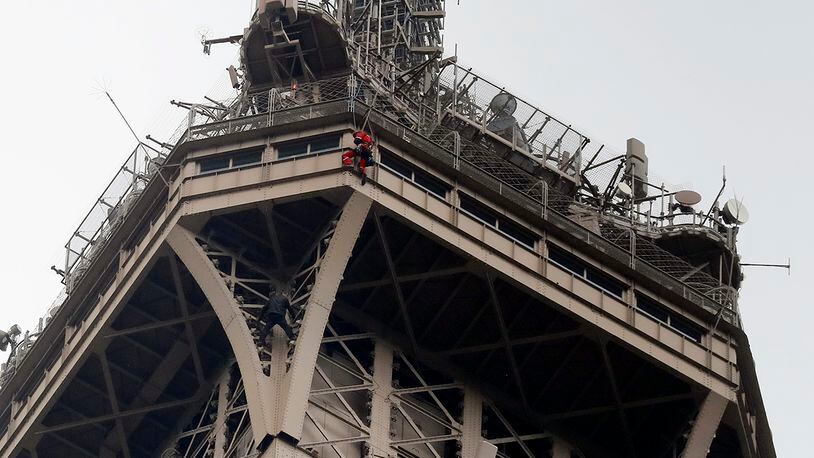 A rescue worker hangs from the Eiffel Tower Monday, May 20, 2019 in Paris. The Eiffel Tower has been closed to visitors after a person has tried to scale it. (AP Photo/Michel Euler)