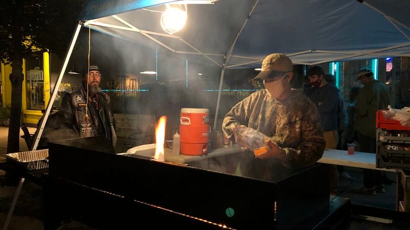 A street vendor in the Oregon District makes hamburgers for customers earlier this month. CORNELIUS FROLIK / STAFF