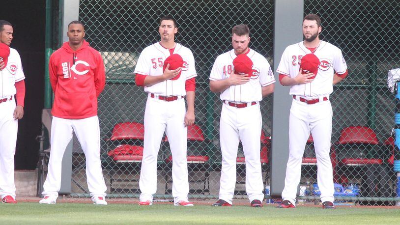 Reds relievers, including Robert Stephenson, center, stand for the national anthem before a game against the Brewers on Thursday, April 13, 2017, at Great American Ball Park in Cincinnati. David Jablonski/Staff