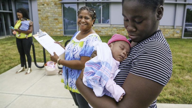 Tiara Thomas holds her baby So-Nae Turner as Natalie Jones, a certified community health worker from Butler County Moms and Babies First, looks on during a PRIM Community Action Team event outside Primary Health Solutions Health Center in Middletown, Tuesday, Aug. 29, 2017. Th PRIM team - consisting of local community leaders, Pastors, advocates and concerned citizens are working together to combat Infant Mortality. GREG LYNCH / STAFF