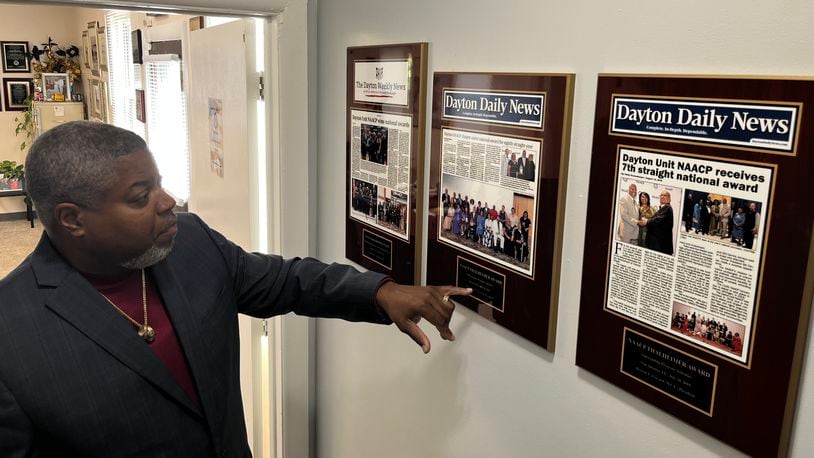 Dayton Unit NAACP President Derrick Foward shows framed news coverage from the Dayton Weekly News and Dayton Daily News, spotlighting awards the organization has won, in the NAACP's new headquarters building on Salem Avenue. JEREMY P. KELLEY / STAFF