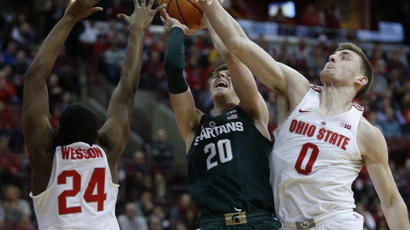 Michigan State guard Matt McQuaid, center, goes up to shoot between Ohio State forward Andre Wesson, left, and center Micah Potter during the first half of an NCAA college basketball game in Columbus, Ohio, Sunday, Jan. 7, 2018. (AP Photo/Paul Vernon)