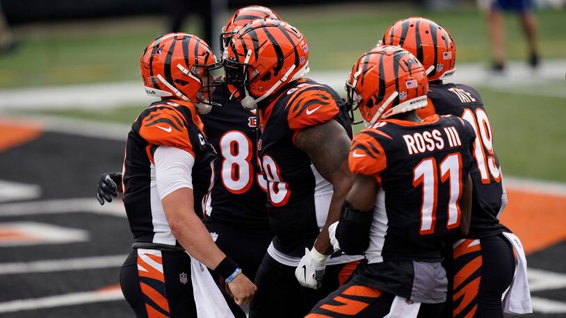 Cincinnati Bengals quarterback Joe Burrow, left, celebrates with teammates after Burrow ran for a touchdown during the first half of an NFL football game against the Los Angeles Chargers, Sunday, Sept. 13, 2020, in Cincinnati. (AP Photo/Bryan Woolston)