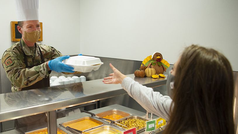 Chief Master Sgt. Troie Croft, Air Force Life Cycle Management Center command chief, hands Airman 1st Class Alex Fulton, 88th Air Base Wing Public Affairs Office, a Thanksgiving dinner. U.S. AIR FORCE PHOTO/R.J. ORIEZ