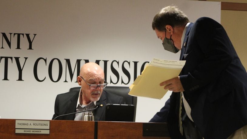 Montgomery County Board of Elections Director Jeff Rezabek hands documents to board member Thomas Routsong at a meeting this week. CORNELIUS FROLIK / STAFF