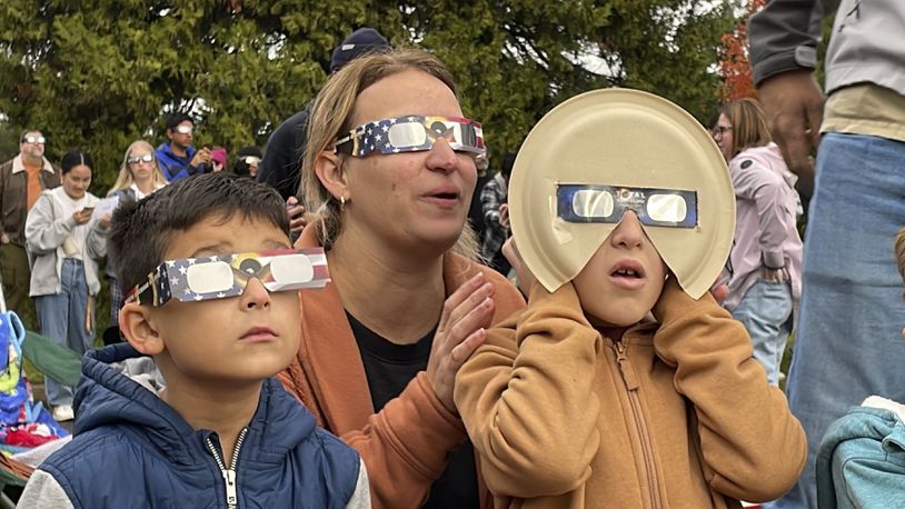Samia Harboe, her son Logan and her friend's son wear eclipse glasses during totality of the annular solar eclipse in Eugene, Ore., on Saturday, Oct. 14, 2023. Her family came with glasses they'd made for the 2017 total eclipse and said they were excited to see another one. (AP Photo/Claire Rush)
