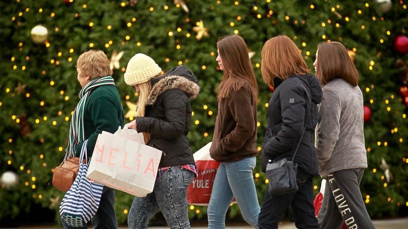 Black Friday shoppers walk past the large Christmas tree on the Greene Town Center in Beavercreek. JIM WITMER / STAFF