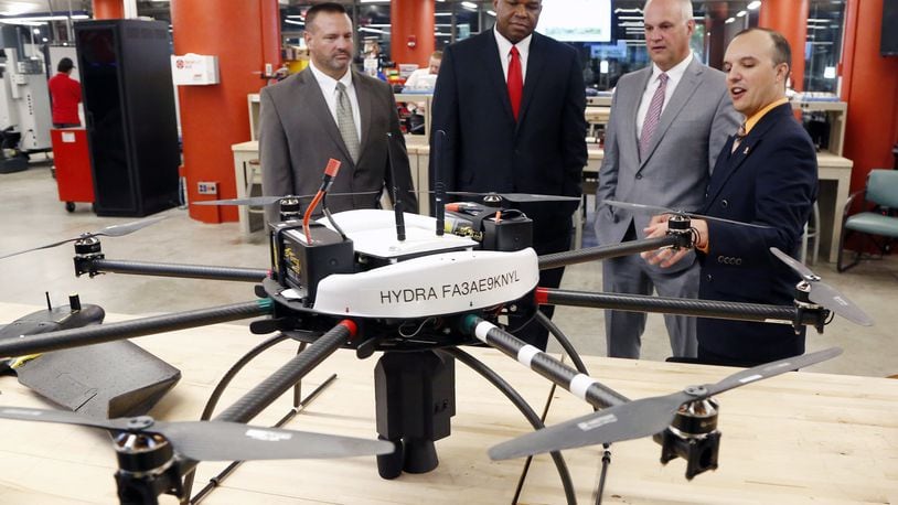 Andrew Shepherd, right, Executive Director & Chief Scientist, UAS, at Sinclair Community College, talks about a large octocopter drone used for research by students. With Shepherd from the left are: Jeff Miller, Chief Operating Officer, UAS, Sinclair, Maurice McDonald, EVP, Aerospace & Defense at the Dayton Development Coalition (DDC) and Scott Koorndyk, President of The Entrepreneurs Center. Sinclair announced on Wednesday that it was awarded a $545K grant to support UAS tech entrepreneurship. TY GREENLEES / STAFF
