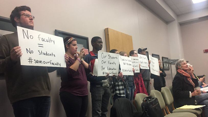 Andrew Blake, left, a senior studying music performance at Wright State, holds a sign to protest recent faculty and staff layoffs during a board of trustees meeting Wednesday. Next to him, Abby Jones and Brendon Sapp also protest. MAX FILBY / STAFF