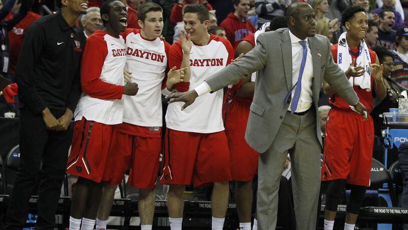 Dayton players and assistant coach Allen Griffin, second from right, watch from the bench in the final minute of a victory against Providence in the second round of the NCAA tournament on Friday, March 20, 2015, at Nationwide Arena in Columbus. David Jablonski/Staff