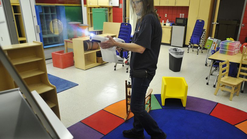 Betty Clark, a custodian for Beavercreek schools, disinfects a preschool classroom with a chlorination gun. Beavercreek was listed as having five student COVID-19 cases last week among its 7,000-plus students. MARSHALL GORBY\STAFF