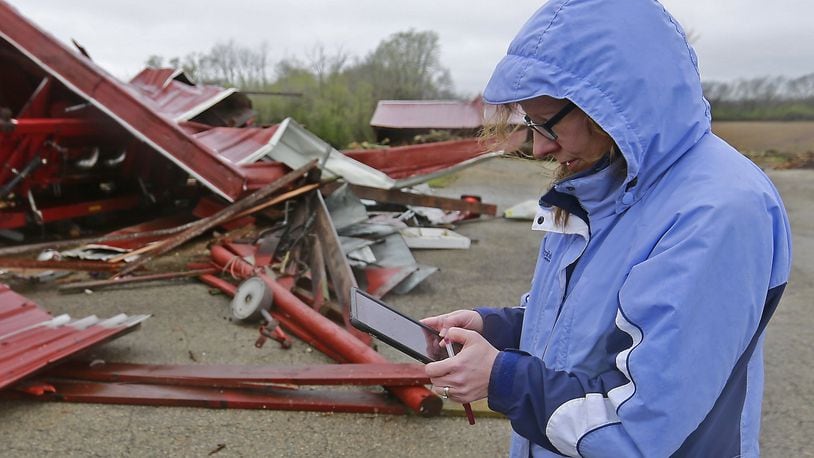 Julie Reed, from the National Weather Service, takes notes as she surveys they damage to a barn in Enon Thursday. Bill Lackey/Staff
