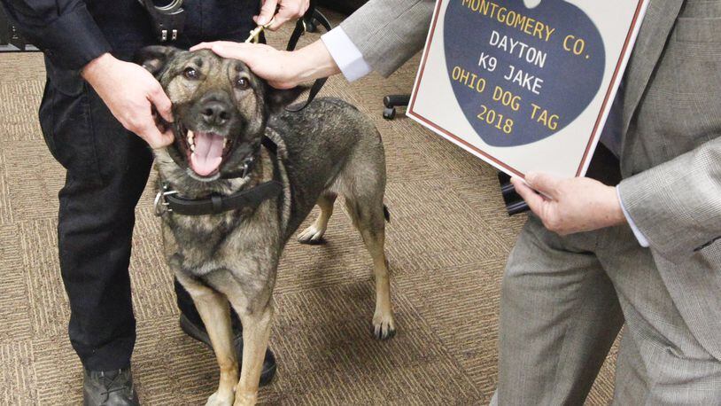 Montgomery County Auditor Karl Keith presents Dayton Police Department K-9 Jake with his 2018 dog license. Keith handed out 2018 licenses to nine police dogs from the Montgomery County Sheriff’s Office, the Dayton Police Department and the Kettering Police Department on Friday. Montgomery County citizens are reminded that do licenses are required by Ohio law and will be on sale online and at about 30 county locations until Jan. 31. CHRIS STEWART / STAFF