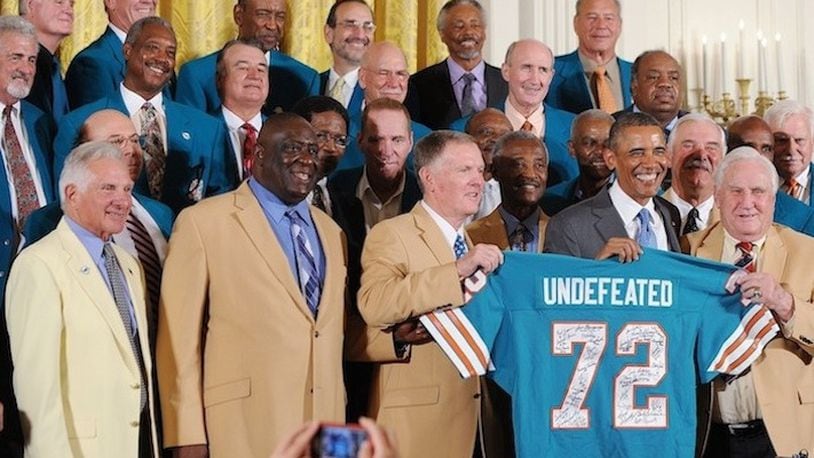 U.S. President Barack Obama holds up a jersey given to him by Miami Dolphins' coach Don Shula, right, after welcoming members of the 1972 Super Bowl champion Miami Dolphins during a ceremony in the East room of the White House on August 20, 2013 in Washington, D.C. (Olivier Douliery/Abaca Press/MCT)