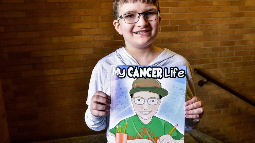 Matthew Harrison, a sixth-grader at Chamberlain Middle School in Carlisle, holds a book he in which he is the star. Sarah Curry Rathel and illustrator Bob Kelly, with Smile Books Project, created the book, “My Cancer Life,” to tell the story of Harrison and his life dealing with Leukemia. NICK GRAHAM/STAFF