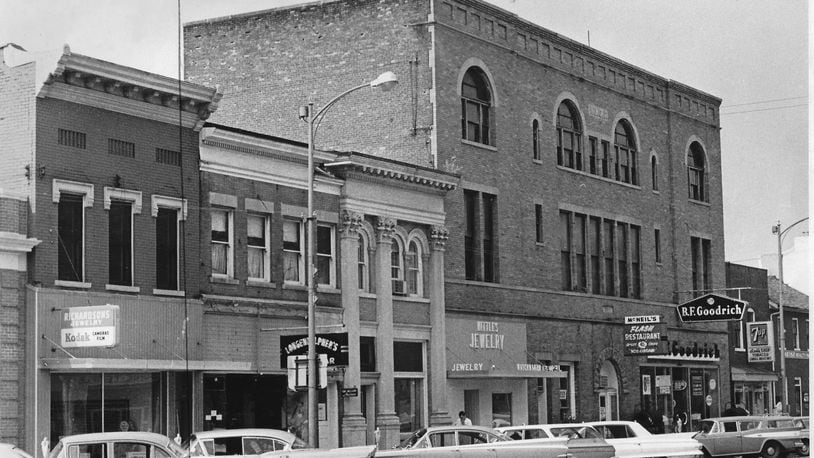 The Flash Restaurant, housed in the building, was a staple of downtown Troy for many decades. It and neighboring businesses are shown in this photograph circa 1964. This building was grafted onto the front of the old Miami County courthouse in 1902.