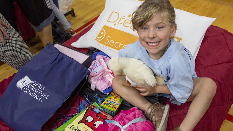 A child just receiving a bed hugs a stuffed animal during the Day to Dream event in 2019.