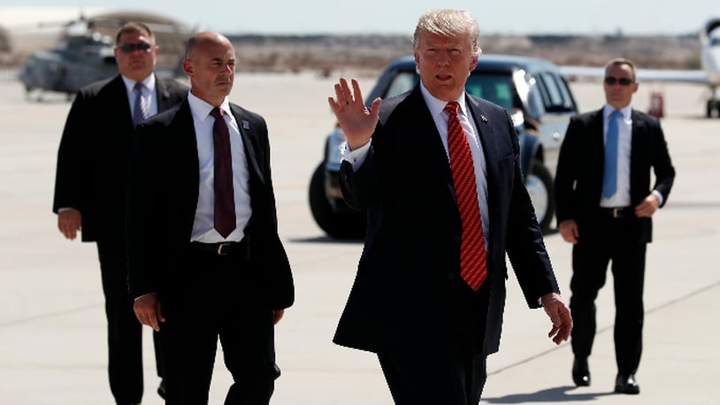 FILE - In this Tuesday, Aug. 22, 2017, file photo, President Donald Trump walks with his U.S. Secret Service protective detail as he waves before he departs on Air Force One in Yuma, Ariz. Some local officials in the border city of Yuma have expressed disappointment in the brevity of President Trump's visit, which they were hoping would give the community a higher profile on the national stage. The Yuma Sun reports that the initial plans for Trump's visit included a visit to the border and possible meetings with farmers and local politicians, but that didn't happen. (AP Photo/Alex Brandon, File)
