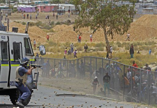A South African policeman. left, fires a rubber bullet, at striking farm workers.