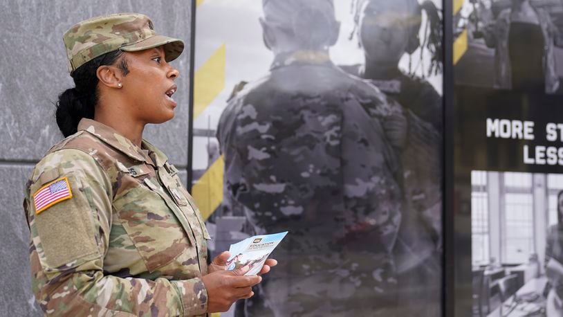 The U.S. Army National Guard member Sgt. Jessica Jones, an officer with the Metropolitan Police Department, distributes brochures to people walking by during training, Thursday, April 21, 2022 in Washington. (AP Photo/Mariam Zuhaib)