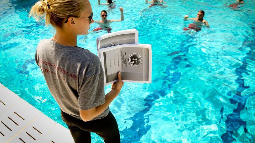 Head Lifeguard Morgan Avers holds pages of a checklist as she monitors lifeguards treading water as they are being trained at the Miamisburg pool in preparation for the summer swimming season. JIM WITMER/STAFF
