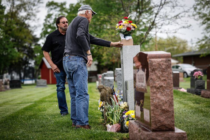 Jim Skokes đặt hoa lên mộ Trung sĩ.  Gary McKiddy tại Nghĩa trang Tưởng niệm Highland ở Miami.  Cả hai đã cùng nhau làm việc tại Việt Nam.  McKiddy đã giải cứu Skokes khỏi một chiếc trực thăng đang bốc cháy và chết trong một vụ nổ trực thăng.  Bên trái là anh trai của McKiddy, Rick McKiddy bên trái.  Jim Nolker / Nhân viên