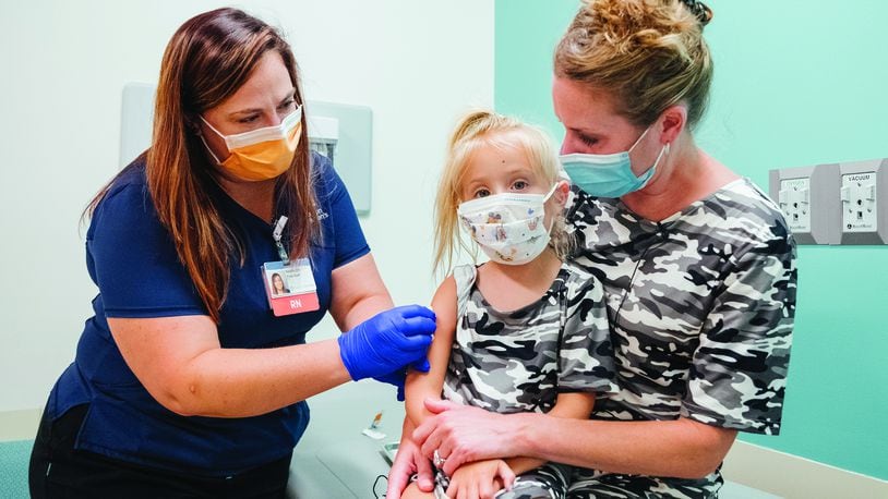 Delaney Bowser (middle) sits with her mom, Kristen Bowser, as Delaney prepares to get her first COVID-19 vaccine at a recent vaccine clinic held at Dayton Children's Hospital. CONTRIBUTED