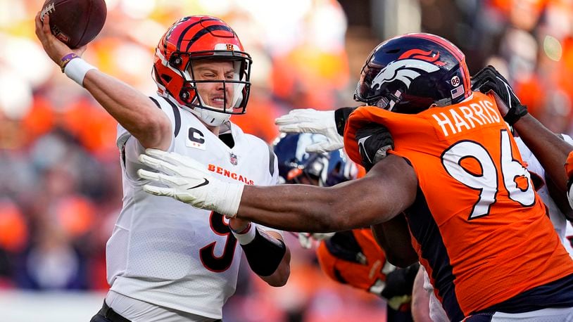 Cincinnati Bengals quarterback Joe Burrow (9) throws under pressure from Denver Broncos defensive end Shelby Harris (96) during the first half of an NFL football game, Sunday, Dec. 19, 2021, in Denver. (AP Photo/Jack Dempsey)