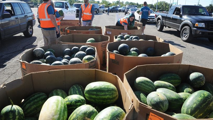 Volunteers handed out watermelons Thursday, Sept. 9, 2021, at The Foodbank Inc. mass food distribution at the Wright State University Nutter Center. MARSHALL GORBY\STAFF