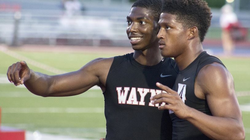 Wayne teammates Justin Harris (left) and Zarik Brown celebrate after they helped win the 1,600-meter relay and clinch the team title over Centerville at Friday’s Division I regional track and field meet at Wayne High School. JEFF GILBERT / CONTRIBUTED