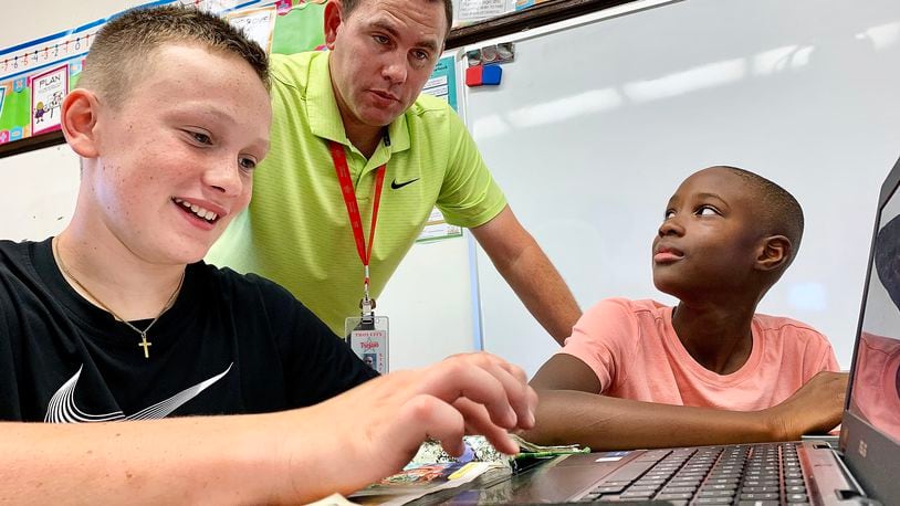Concord Elementary School fifth grade teacher Jacob Wells, works with students, left to right, Jonah Efaw and Jax Johnson Monday Sept. 19, 2022. MARSHALL GORBY\STAFF