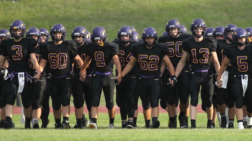 Mechanicsburg players hold hands as they take the field before a game against Kenton Ridge on Friday, Aug. 30, 2019, at Mechanicsburg. David Jablonski/Staff