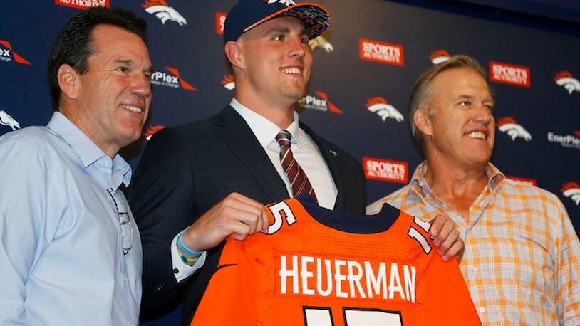 FILE - In this May 2, 2015, file photo, former Ohio State tight end Jeff Heuerman, center, the Denver Broncos third-round pick in the NFL Draft, holds up his new jersey while posing for a photograph with head coach Gary Kubiak, left, and general manager John Elway during a news conference in Englewood, Colo. The Broncos are among several teams that have changed the way they handle rookie minicamps in the two years since two prized picks sustained season-ending knee injuries less than a week after all the hugs and handshakes of draft night. Locker rooms, fan bases and front offices alike were jolted when defensive end Dante Fowler, the third overall pick in 2015, blew out his left knee on the first day of Jacksonville's rookie minicamp. Twenty-four hours later, Heuerman tore his left ACL covering a kickoff.  (AP Photo/David Zalubowski, File)